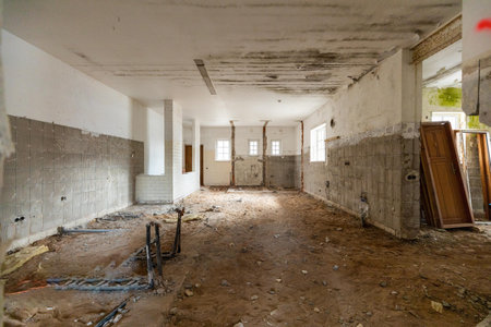 Abandoned building interior in disrepair with debris, exposed pipes, and missing doors awaiting renovationの写真素材