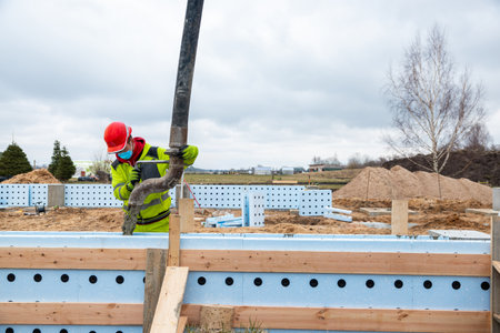 Construction Worker Precisely Operating Concrete Pump at New Building Site Foundationsの写真素材