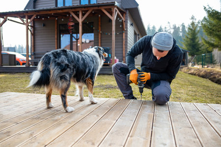 Man working on a deck or terrace  with his loyal dog companion in the yard of a countryside homeの写真素材