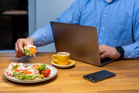 Businessman enjoying a healthy meal and coffee while working at a modern workspaceの写真素材