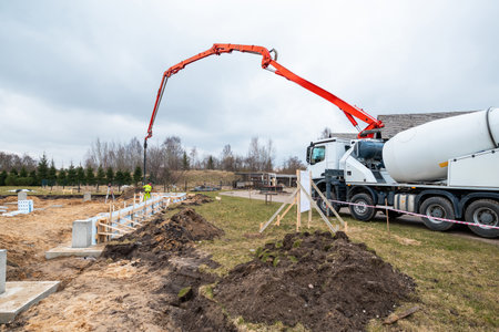 Construction Worker Precisely Operating Concrete Pump at New Building Site Foundationsの写真素材