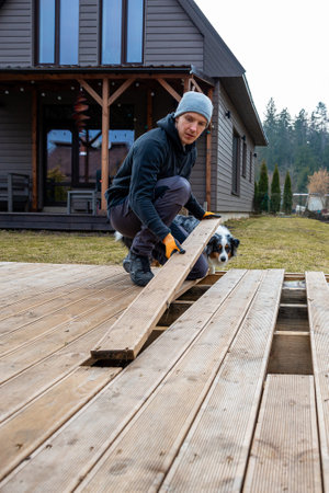 Man working on a deck or terrace  with his loyal dog companion in the yard of a countryside homeの写真素材