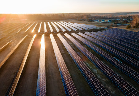 Aerial view of industrial sized solar panel farm during sunset,  illustrating the blend of...