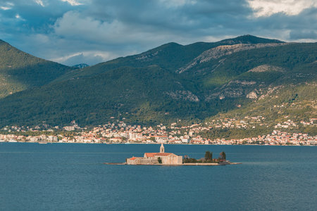secluded monastery island against a mountainous coastal town backdropの写真素材