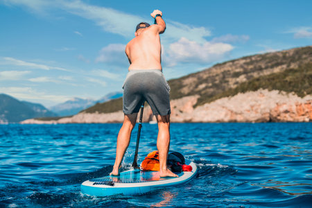 adventurous man paddleboarding in the open sea looking towards the horizonの写真素材