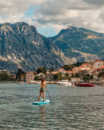 female paddler on inflatable sup board amidst stunning mountainous landscape and turquoise watersの写真素材