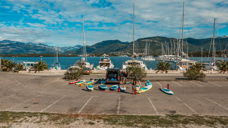 Scenic Marina with Mountains in Background and Colorful Paddle Boards Lined Up on Sunny Dayの写真素材