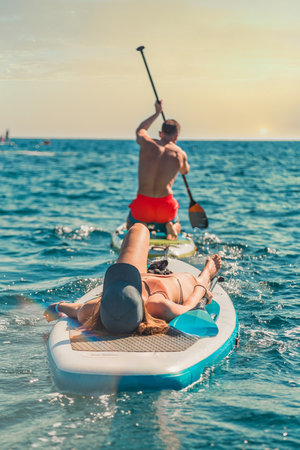 relaxed woman resting on a SUP paddleboard on a sunny day in a calm riverの写真素材