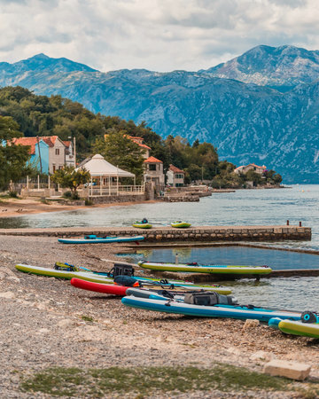array of colorful paddleboards on a pebbled lakeshore ready for adventure