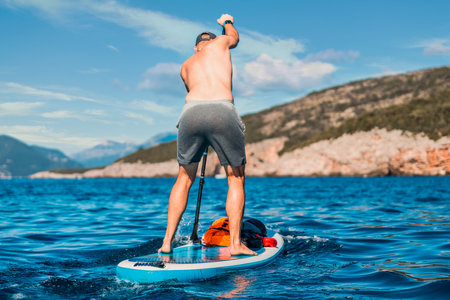 adventurous man paddleboarding in the open sea looking towards the horizonの写真素材