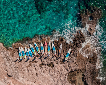 SUP paddleboards lined up on rocky shoreline with crystal clear turquoise watersの写真素材