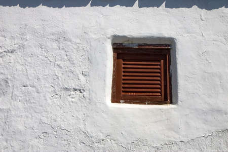 Old shuttered window in a whitewashed wall