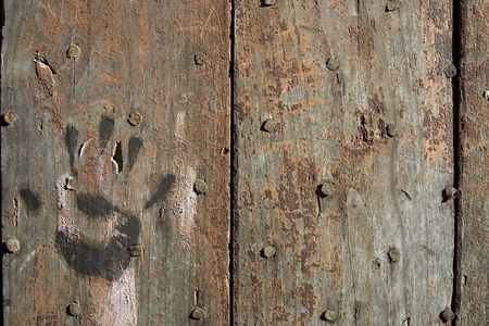 A handprint on an ancient nailed wooden doorの写真素材