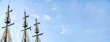 The masts of the old ship on the background of the blue sky. The concept of travel Copy space and...