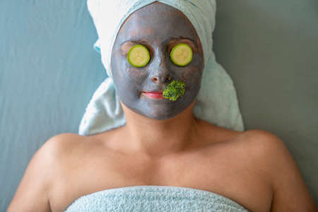 Young woman with cosmetic mask and natural vegetables on face. Concept of natural cosmeticsの写真素材