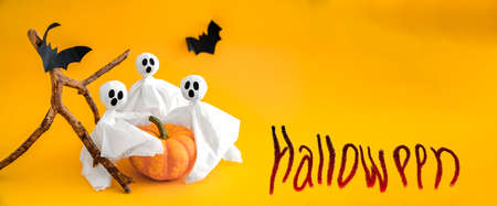 Ghosts, pumpkin and bats on orange background with inscription Halloween. Banner, copy spaceの写真素材