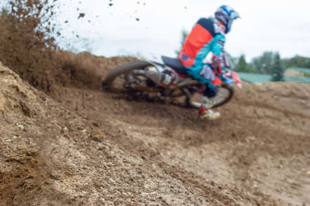 Blurred silhouette, motorcycle racer enters turn on racing dirt track, earth is flying around. Concept of extreme.の写真素材
