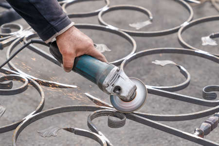 Metal grinding with angle grinder. Male hand and instrument. Working with metal.の写真素材