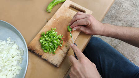 Man cuts vegetables on cutting board for picnic. Process of making salad outdoors, hands close-up.の写真素材