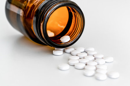 Scattered White Round Vitamins and Brown Vial, Close-Up on White Background, Pharmaceutical Suppliesの写真素材