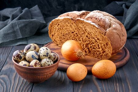 Pumpernickel - bread made with a combination of rye flour and whole rye grains. Quail and chicken eggs, onion. Rustic style, wooden cutting board, pottery, linen, pine table. Fresh healthy farm food.の写真素材