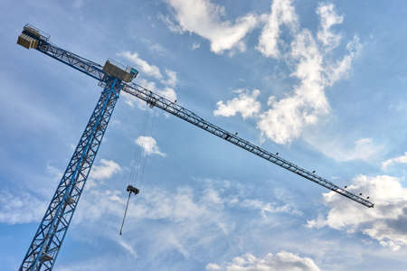 Tower cranes for lifting loads in the construction of tall buildings. Tall construction cranes against the cloudy sky.の写真素材