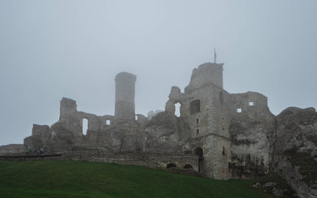 medieval castle ruin sitting on top of hill in heavy fogの写真素材
