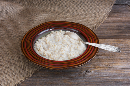 Oatmeal porridge with spoon in plate on wooden table. Tonedの写真素材