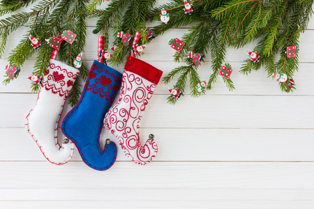 Christmas background. Colorful Christmas socks on white wooden background with Christmas fir tree,...
