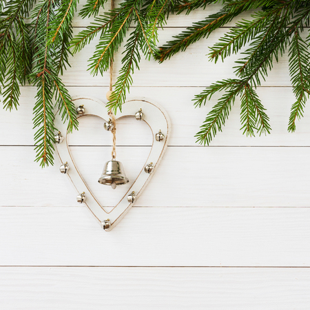 Christmas fir tree branch with white heart and bells. Christmas backgroundの写真素材
