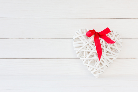 White heart with red bow on white wooden background. Valentine day backgroundの写真素材