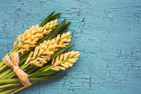 Bouquet of yellow hyacinths decorated with lace on  blue background. Top view, copy space, tonedの写真素材