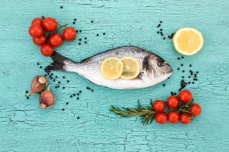 Raw dorado fish with garlic, lemon and tomatoes. Top view, copy spaceの写真素材