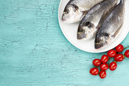 Fresh dorado fish on white plate on blue background. Top view.の写真素材