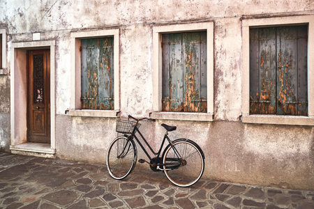 Old rusty bicycle against the old wall on the street. Italy, Venice, Burano islandの写真素材
