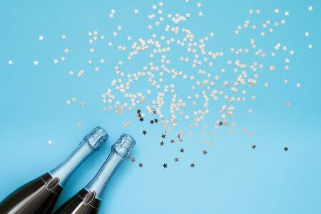Two Blue Champagne bottle with confetti stars on light blue background. Flat lay of christmas, anniversary, bachelorette, new year celebration concept. Copy space, top viewの写真素材