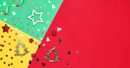 Colorful Christmas background. Christmas decoration and star shape glitters on red, green and yellow backdrop. Copy space, top view.の写真素材