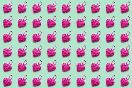 Pink wicker heart on green background. Seamless pattern. Valentines day concept, top viewの写真素材
