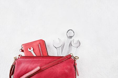 Wrenches spanner and a phone stick out from a small red women bag. Strong woman concept. Top view,...