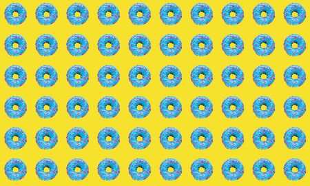 Pattern of a blue donut on a yellow background. Flat lay