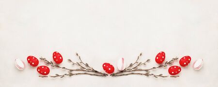 Easter banner. Red and white Easter eggs and willow branches on white concrete background. Top view,...