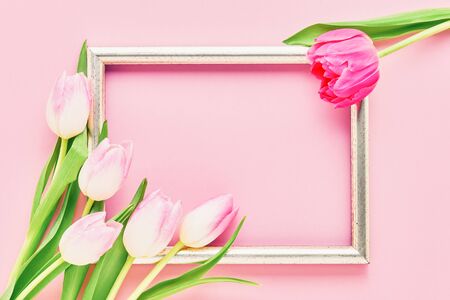 Golden frame with pink tulips on pink background. Mockup. Top view, copy space for text.の写真素材