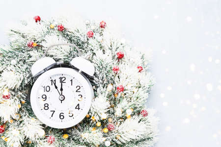 Christmas background. Christmas wreath with decoration and white alarm clock on blue background....