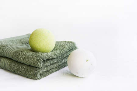 SPA concept. Bath bombs and two green towels on light background. Copy space for text.