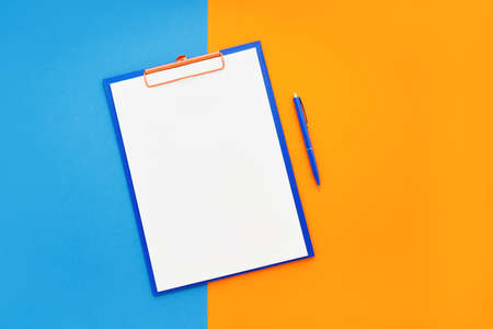 Blank clipboard mockup and blue pen on blue-orange color background. Top view, copy space for text....