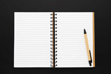 Recycled paper notebook opened on an empty sheets on black background. Copy space for text, top...