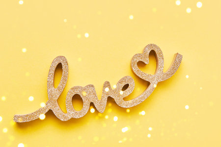 Valentines Day concept background. Golden word LOVE on yellow background. Top view, copy spaceの写真素材