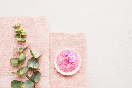 Rolled towels, bath salt and eucalyptus branch on light background. SPA, hygiene, wellness wellbeing, body care concept.の写真素材