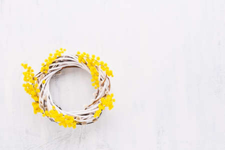 Spring or Easter background. Easter wreath decorated with mimosa flowers on white background. Top...