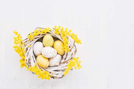 Easter eggs and mimosa wreath on a white background. Top view, copy space for textの写真素材